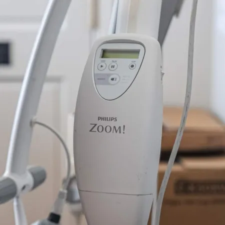 Close-up of Philips Zoom! teeth whitening device with control panel and power cords in dental clinic.