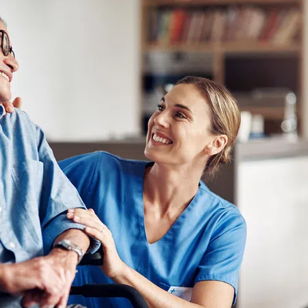 Healthcare professional smiling at elderly patient in a caring environment.