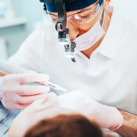 Dentist performing a dental procedure on a patient in a clinical setting with modern equipment.