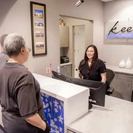 Dental office reception with staff greeting elderly patients at Keene Smiles front desk area.