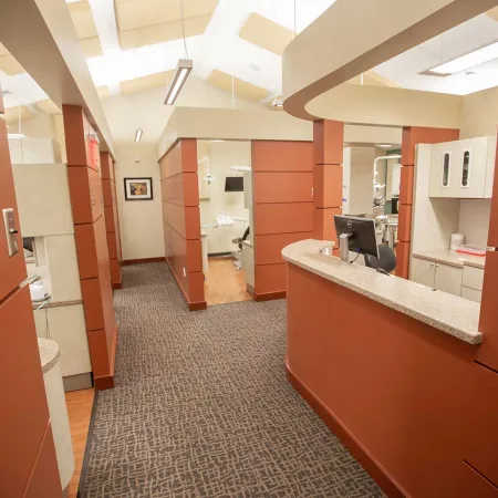 Modern dental clinic interior with reception desk, exam rooms, and warm earth tone decor under bright lighting