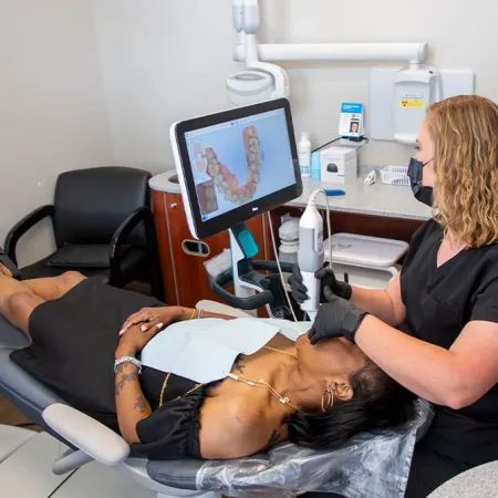 Dental technician uses intraoral scanner to capture patient's teeth digital impression in modern clinic.