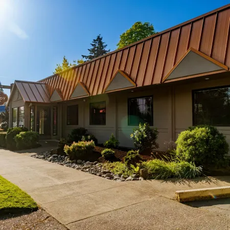 Exterior view of Kennedy Dental clinic with modern metal roof, landscaping, and clear sunny sky.