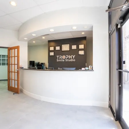 Modern dental office reception area with Trophy Smile Studio sign and waiting room seating.