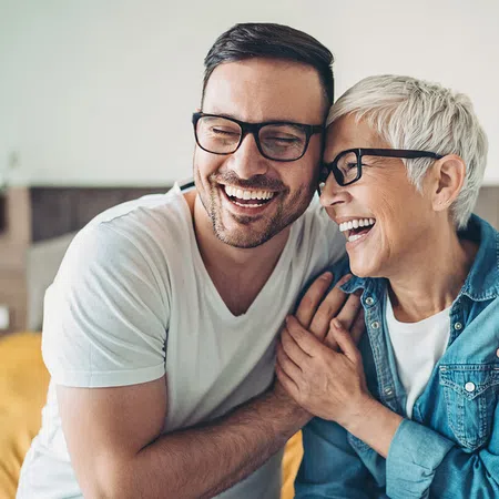 Happy man and woman laughing together in a cozy indoor setting, showcasing warmth and joy.