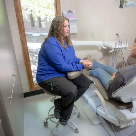 Dentist and patient in consultation in a dental office with equipment and natural light from window