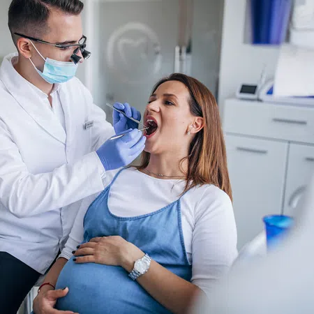 Pregnant woman receiving dental check-up from a professional dentist in a modern clinic.