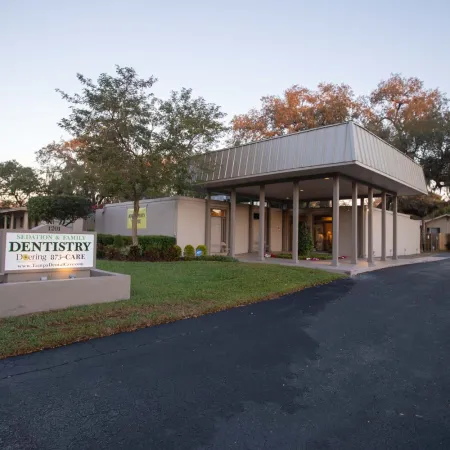 Modern dental clinic building with a Sedation & Family Dentistry sign on a grassy lawn at dusk