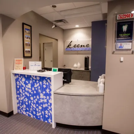 Reception area of Keene Smiles dental office with blue floral desk and awards on beige walls