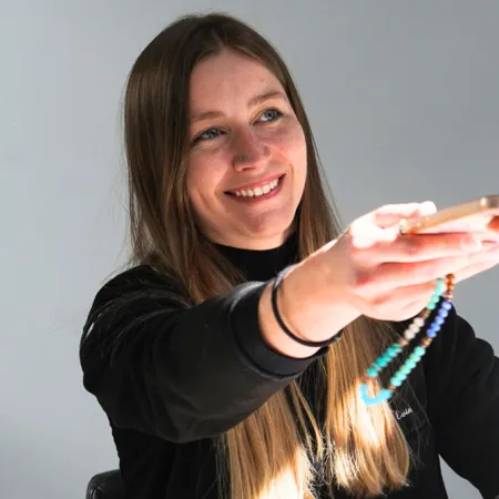 Young woman smiling while handing a smartphone, with a focus on friendly interaction and engagement.