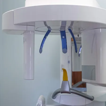 Close-up of a modern dental panoramic X-ray machine with blue handles and a patient positioning arm.