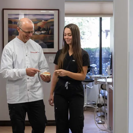Dentist and dental assistant discussing a dental model in a bright, modern dental office with natural light.