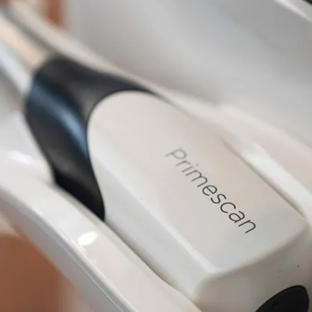Close-up of a white and black Primescan dental scanner device resting in its holder.