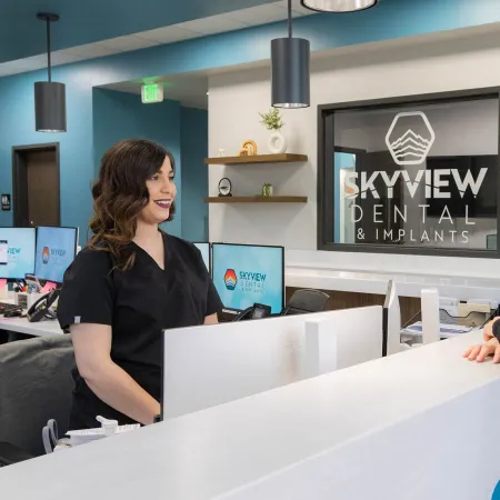 Dental receptionist assisting a woman patient at Skyview Dental & Implants modern reception desk.
