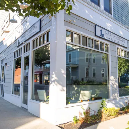 Bright exterior of Martin's Dental office on a sunny day with large windows and surrounding greenery.