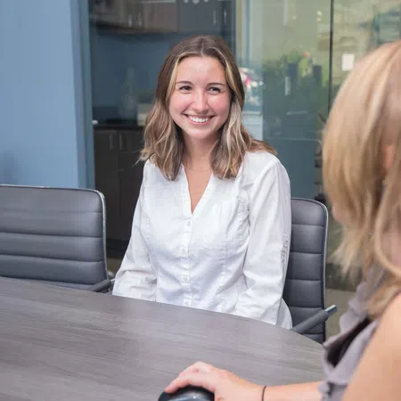 Two women engaged in a friendly business meeting at a modern office conference table.