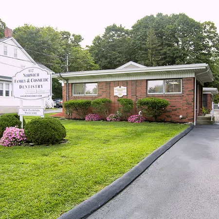 Brick dental office with manicured lawn, flowers, and signage for Norwich Family & Cosmetic Dentistry.