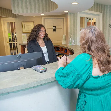 Patient speaking with receptionist at Norwich Family & Cosmetic Dentistry office reception desk.
