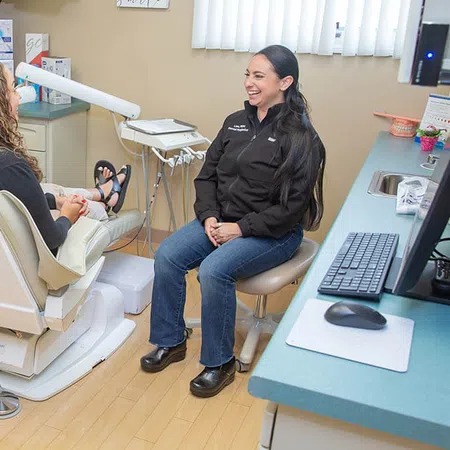 Dentist and patient smiling during consultation in a modern dental office with clean equipment and computer setup.