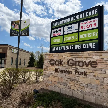 Outdoor sign for Greenwood Dental Care and other businesses at Oak Grove Business Park on a sunny day.