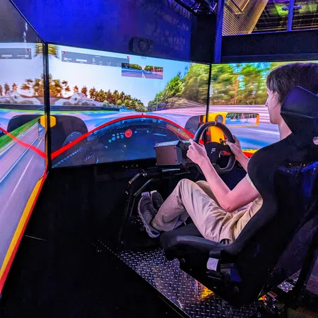 Person racing in a high-tech simulator with immersive screens and realistic steering controls.