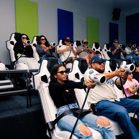 Group of people wearing 3D glasses playing immersive virtual shooting game in a modern arcade room.