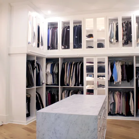 a white room with a white table and shelves with clothes on it