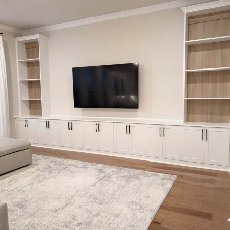 a room with a tv and white cabinets