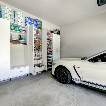White Ford Mustang GT350 parked in a clean garage with organized white storage cabinets and shelves