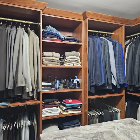 a closet with clothes and a bed