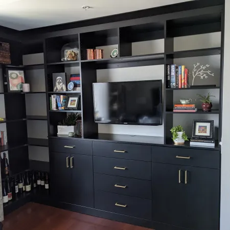 a black cabinet with a tv and shelves with objects on it