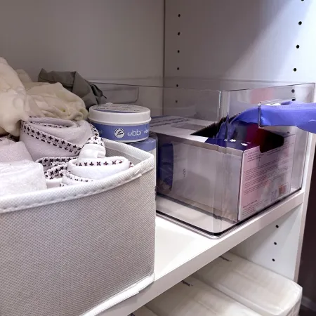 a room with a bed and a shelf with a white box and a white pillow