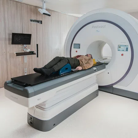 Patient lying on a table entering a Radixact radiotherapy machine in a modern clinical room.