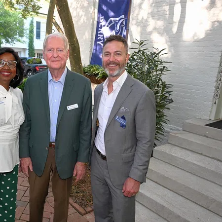 Three professionals smiling outdoors near a Berry College dual degree engineering program sign and greenery.