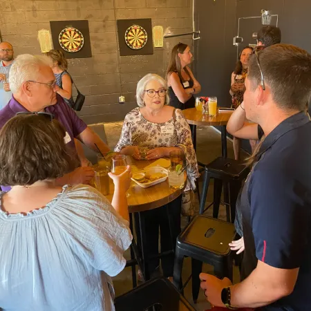 a group of people standing around a man sitting at a table