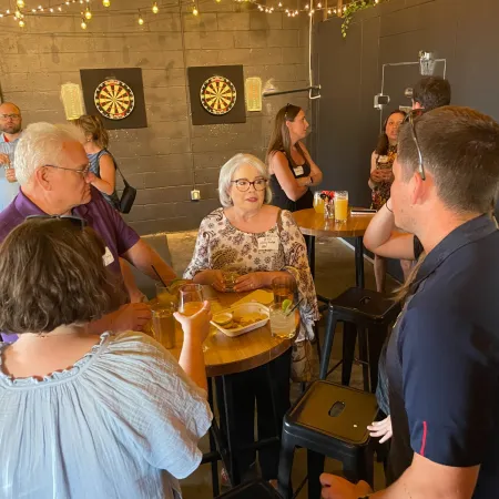 a group of people standing around a man sitting at a table