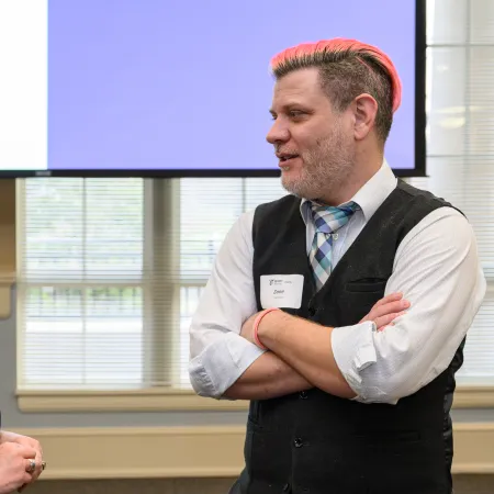 Two professionals with name tags engage in conversation at an indoor event with Berry Alumni visuals.