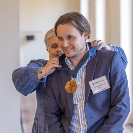 Young man receives a medal award from a woman during a professional indoor ceremony.