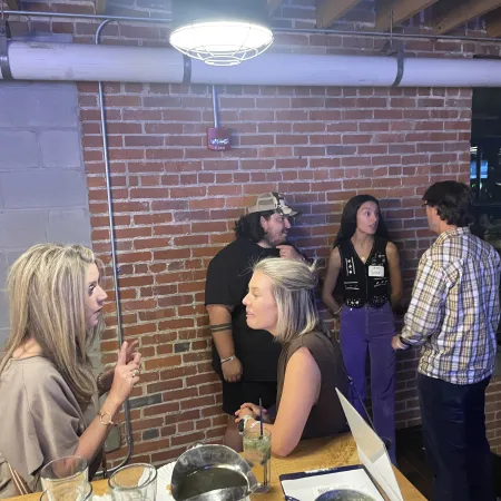 a group of people standing around a table with food and drinks