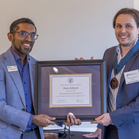 Two men in business attire holding a framed certificate awarding Drew Dillard with Entrepreneurial Spirit recognition.