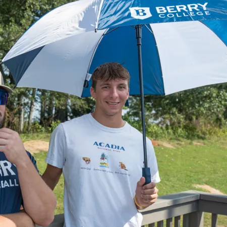 a couple of men sit under an umbrella