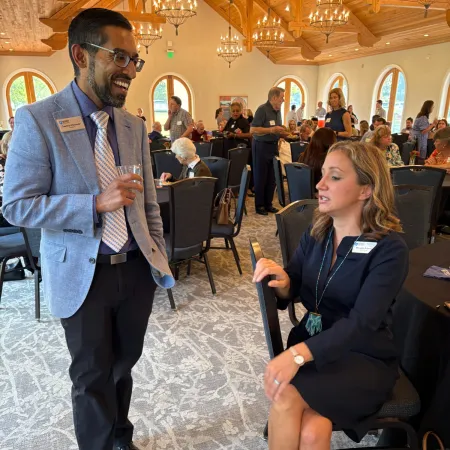 Man and woman in business attire engaged in conversation at a networking event in a bright venue.
