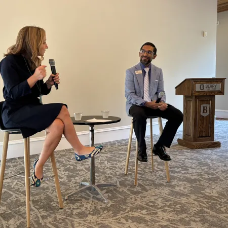 Two professionals seated on stools having a discussion with microphones in a conference room at Berry College.