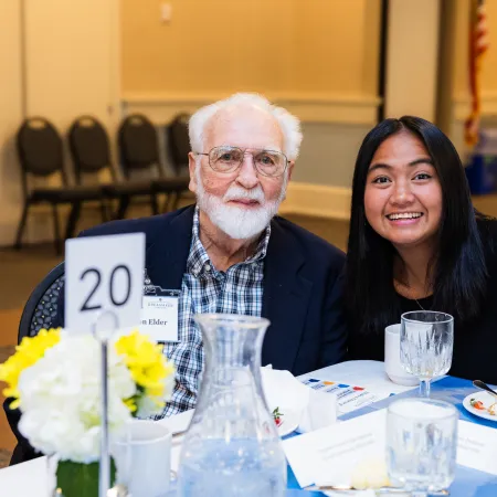 Carl Djerassi et al. sitting at a table with flowers