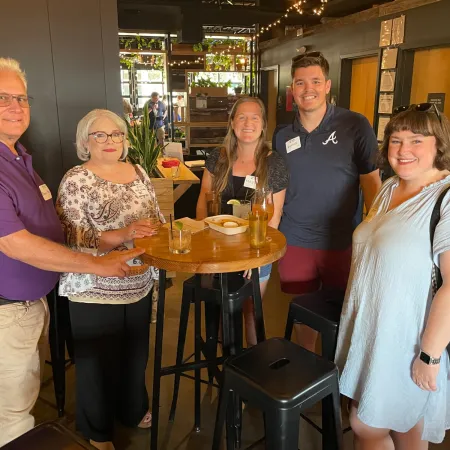 a group of people standing around a table with drinks on it