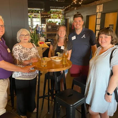 a group of people standing around a table with drinks on it