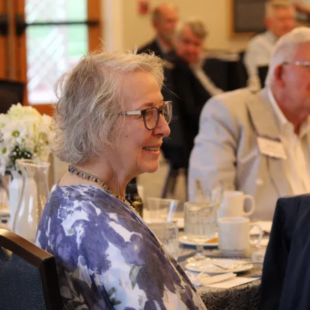 Smiling elderly woman and man seated at a dining table during a social gathering indoors