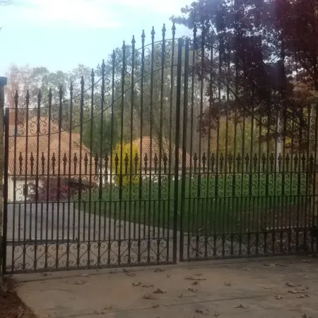 a gate with a stone wall and trees in the background