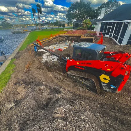 Cantsink skid steer installing helical piles for pool foundation