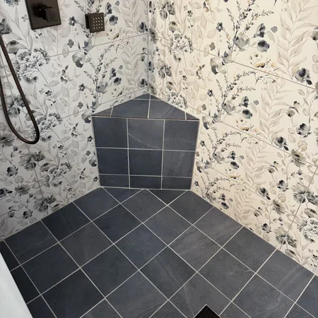 Shower corner with dark gray floor tiles, floral patterned wall tiles, and square shower fixtures.